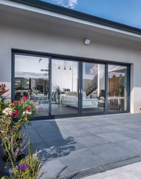 Grande baie vitrée coulissante en aluminium ouvrant sur une terrasse